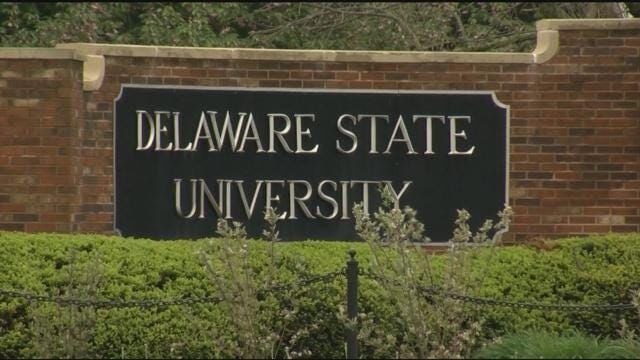Black Delaware State University sign on a low brick wall