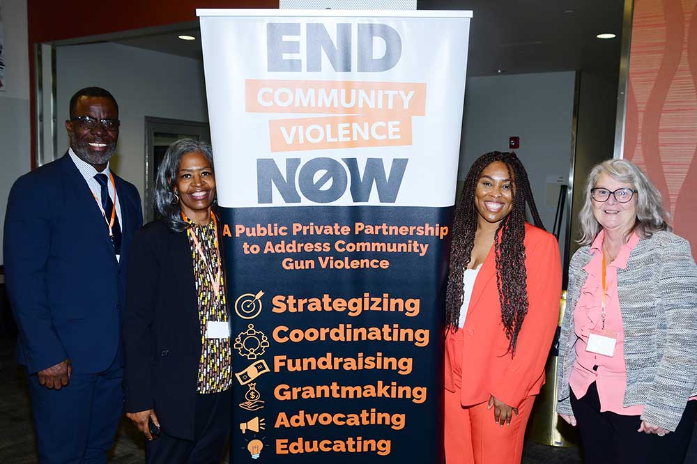 2 Black women standing on each side of an End Community Violence Now banner