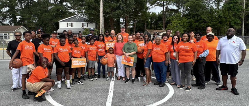 A large group of people in red shirts standing on an outdoor basketball court